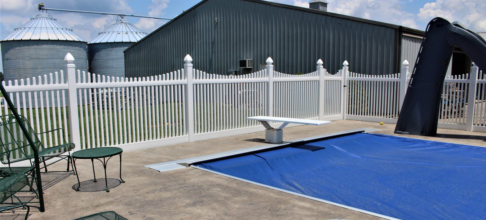 Photo of a white vinyl picket fence surrounding an inground pool